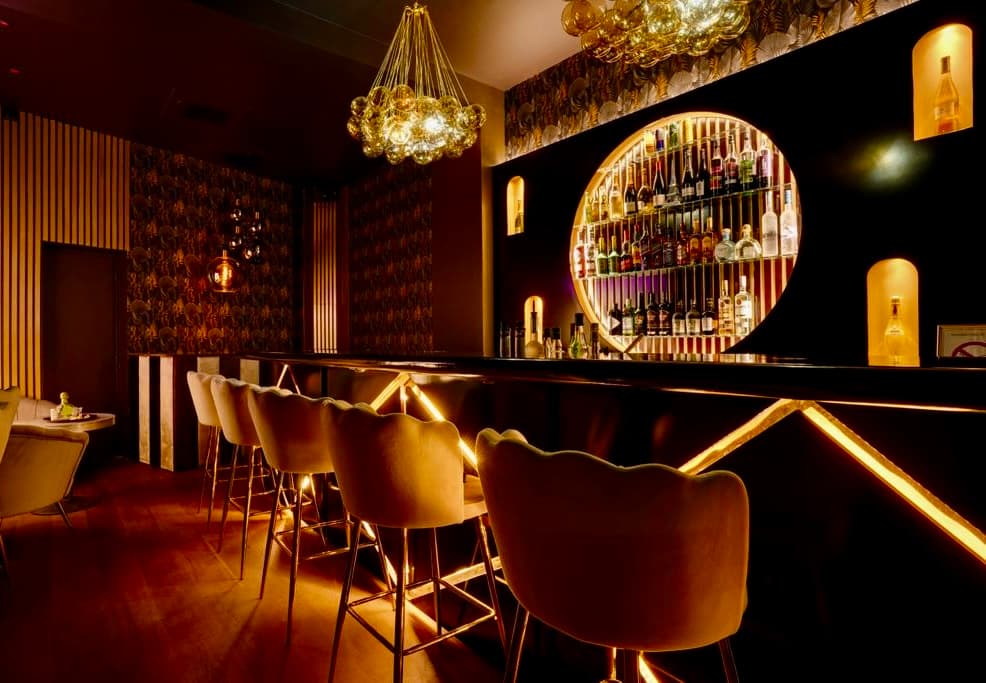 Comptoir du bar avec arches dorées et étagères chez La Perla 17ème
