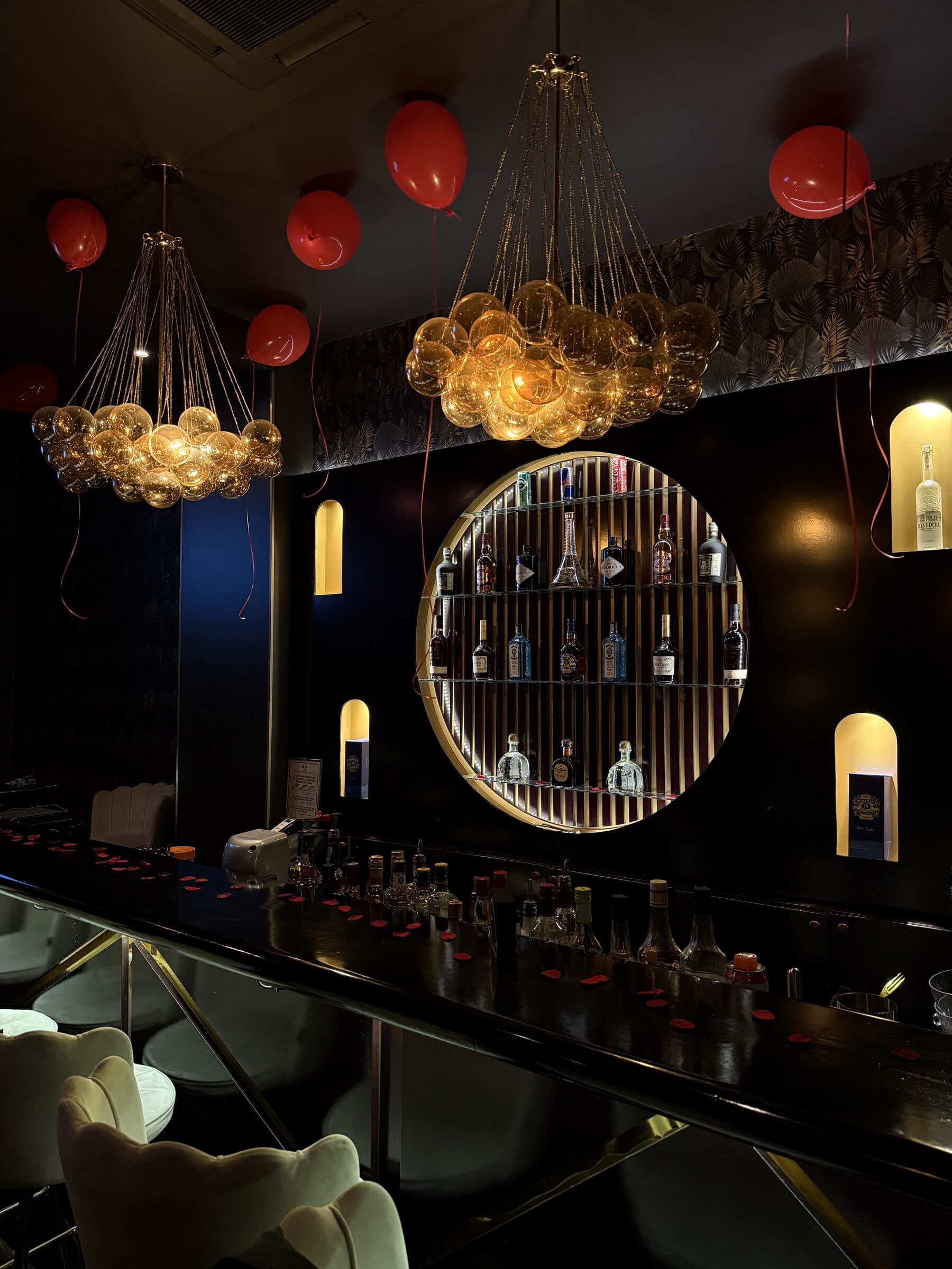 Vue plongeante du bar avec lustres en bulles et présentoir de spiritueux chez La Perla Paris
