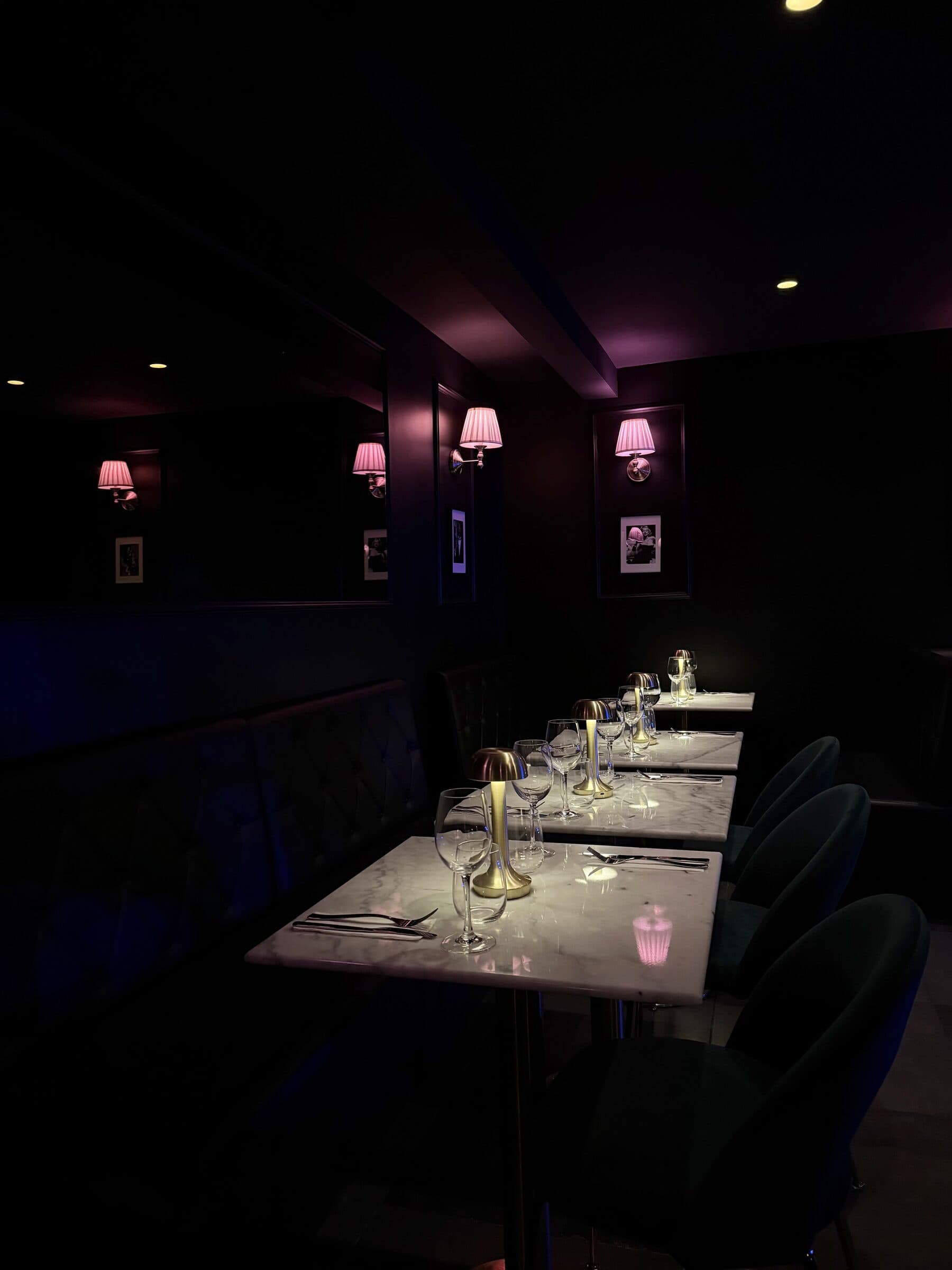 Salle à manger du lounge La Perla avec lampes murales roses et tables en marbre à Paris 17