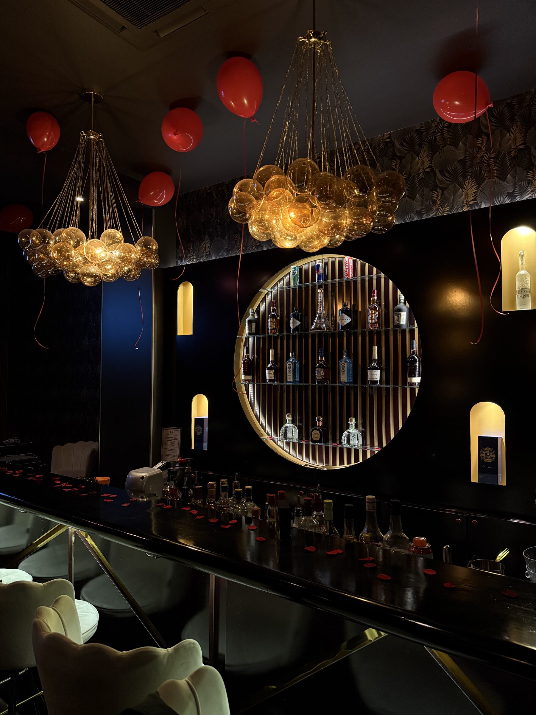 Overhead view of the bar with bubble chandeliers and spirits display at La Perla Paris