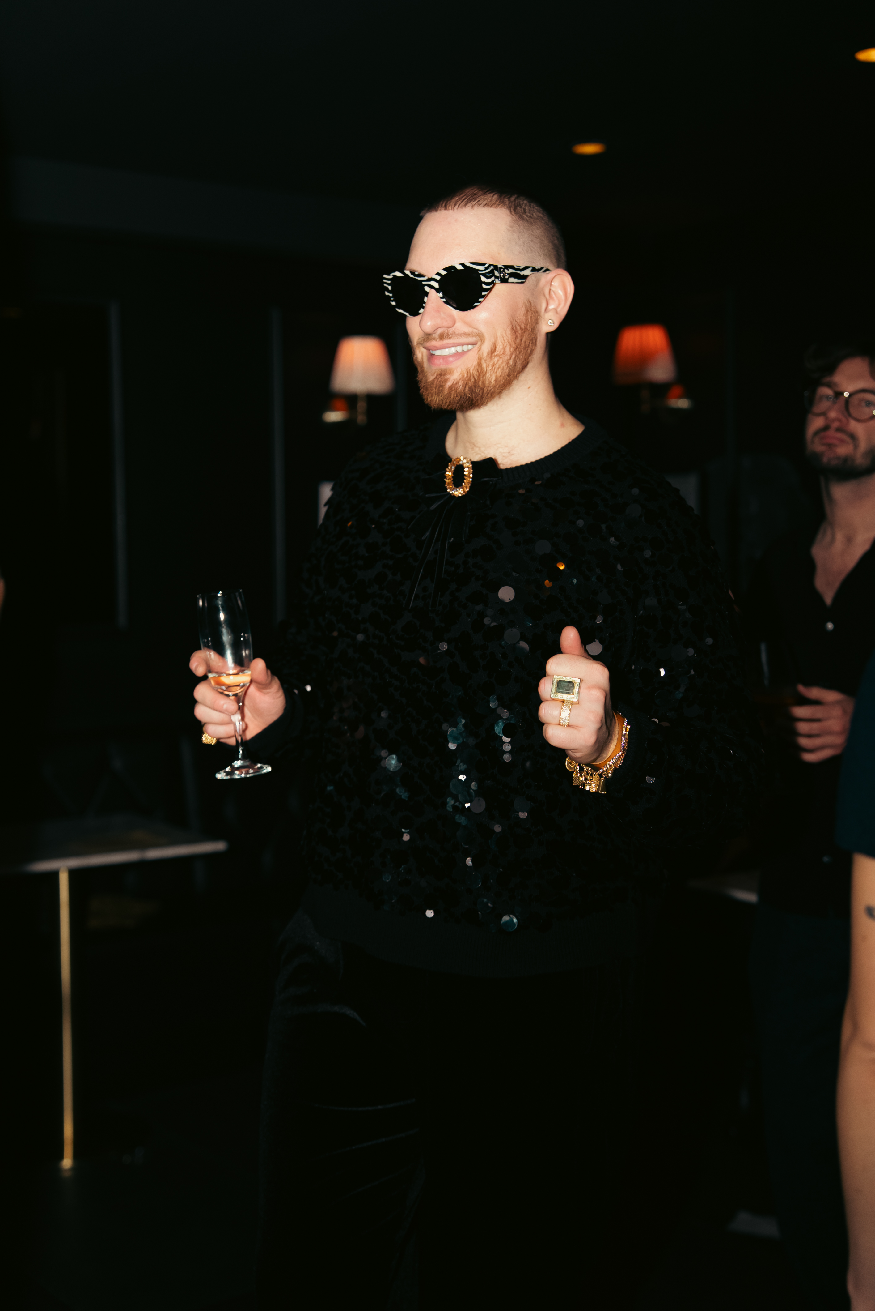 Guest in sequin outfit with champagne flute during a private event